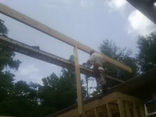 Carpenter setting a ridge beam over a new addition frame — Ice Dam Removal by Roofing Brothers in Middle River