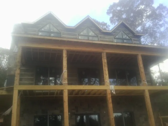 Dormers and porch framing on a large log home under construction — Roof Coating work by our crew in Middle River