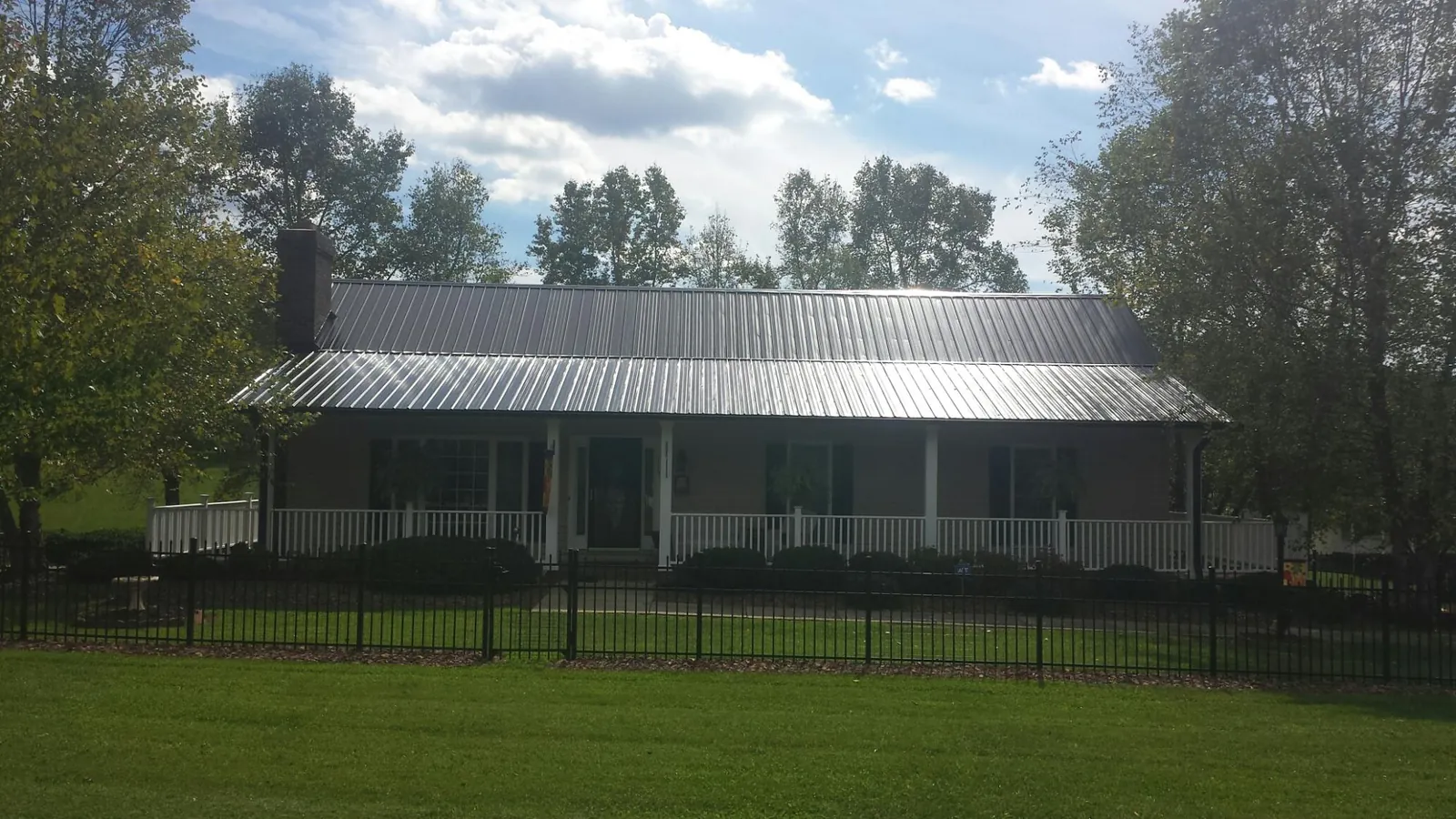 Gray metal roof on a brick ranch with a full width front porch — Gutter Guard Installation work by our crew in Middle River