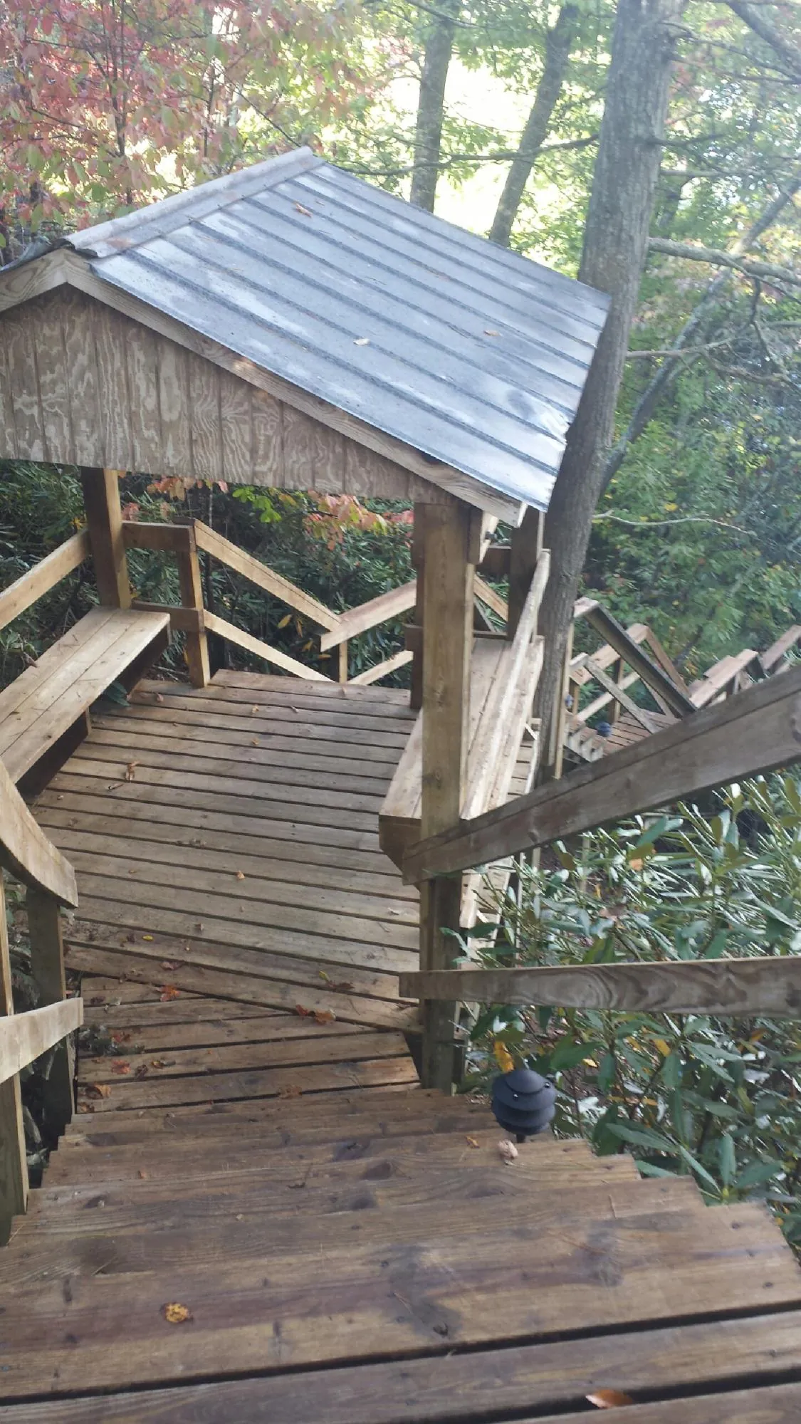 Metal roofed shelter over wooden steps on a wooded walkway — Skylight Repair & Installation work by our crew in Middle River