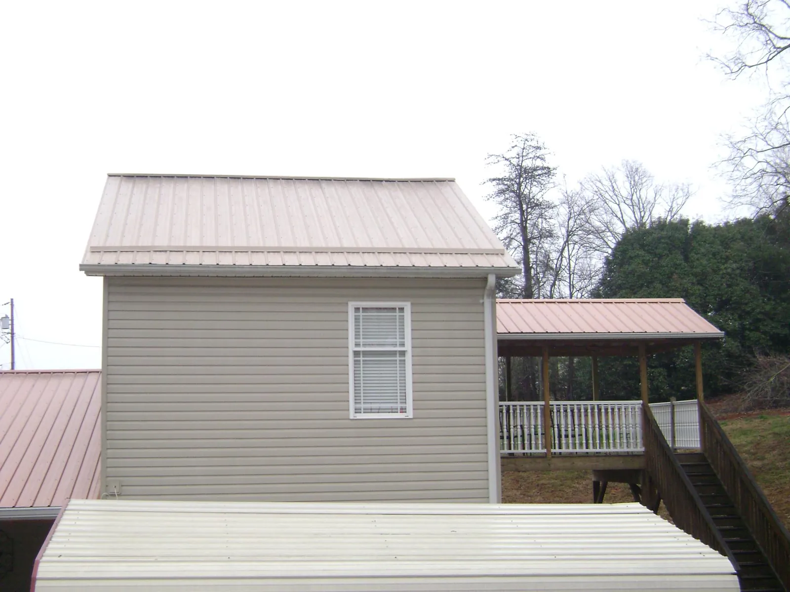 Tan metal roofs on a two story addition and attached porch, from a Roof Replacement job in Middle River